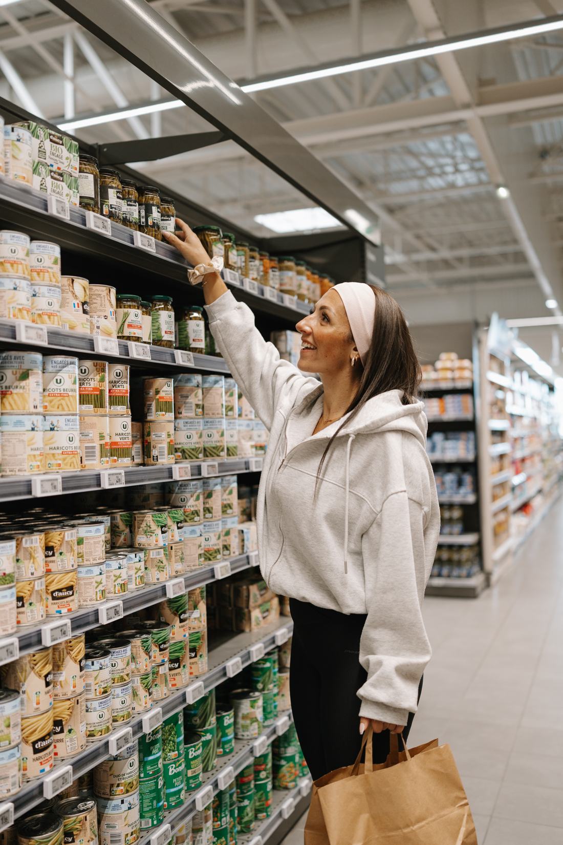 Clémence attrape un bocal de haricots verts au supermarché